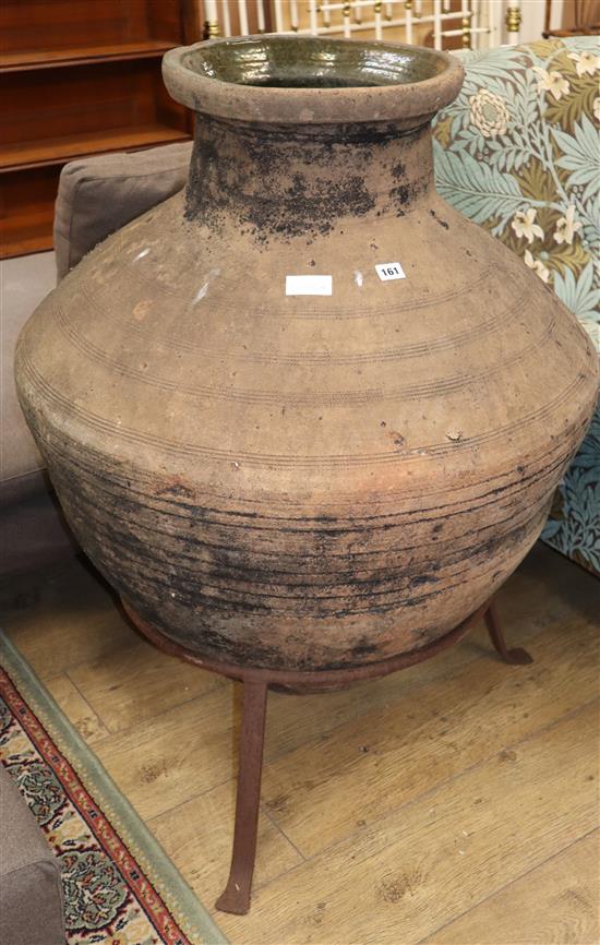 A large glazed pottery oil jar, on wrought iron stand, H.102cm